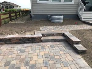 Borgert stairs and bricks create a graceful descent from the double-raised patio near the home to the lower outdoor living area.