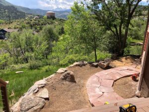 The boulder retaining wall holds up a red flagstone sidewalk/accent in the front of this Lyons, CO home.