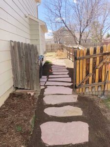 Accenting the walkway on the side yard, are red sandstone pavers added by SR Custom Stone.